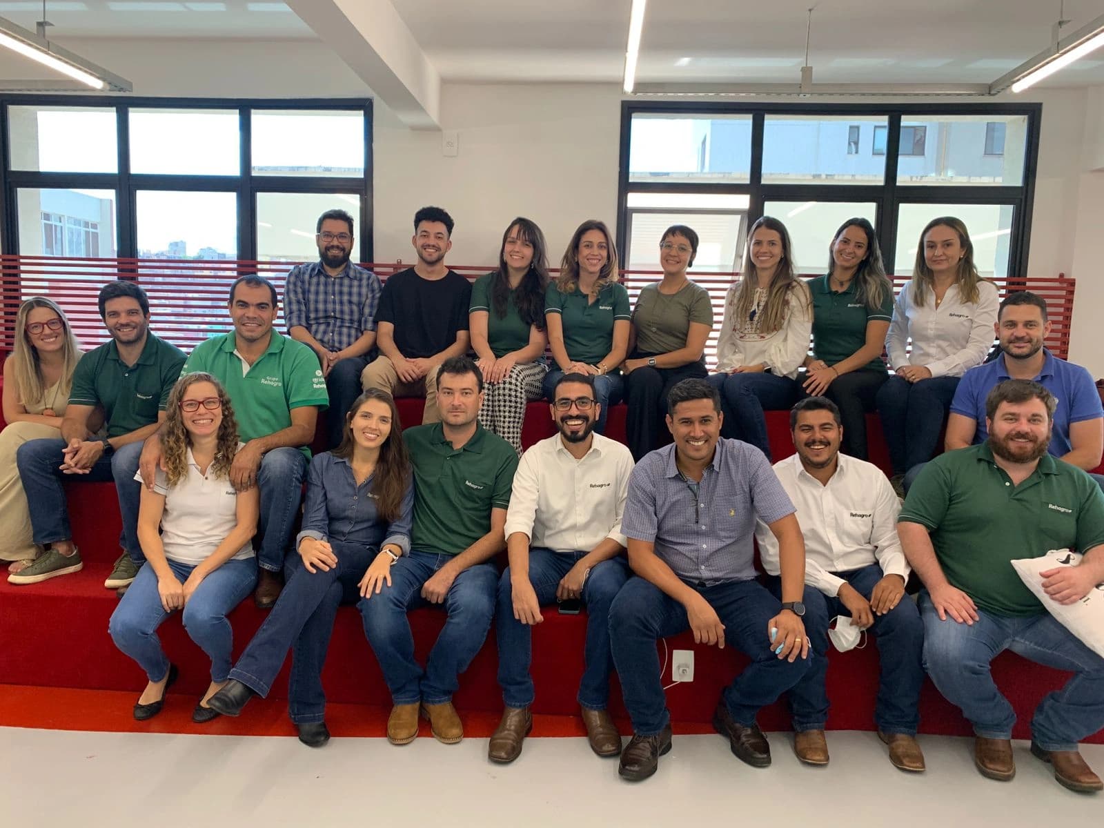 Foto em grupo da equipe do Design Sprint, reunida nas arquibancadas vermelhas do escritório.